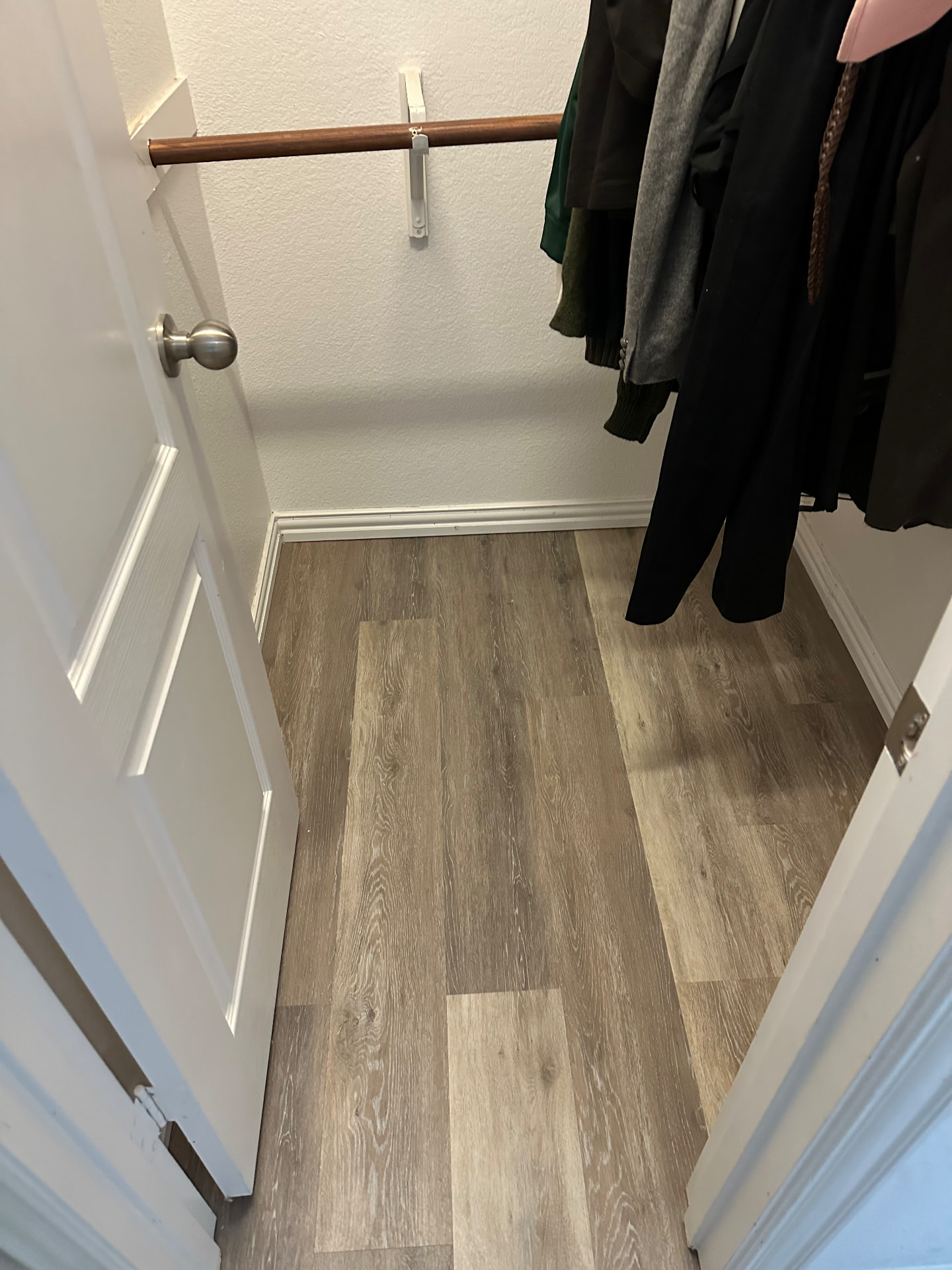 Gray wood-look plank flooring continuing into a closet, seen through an open white door